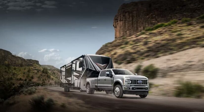 A silver 2024 Ford F-350 is shown towing a trailer to view a Ford Super Duty for sale.