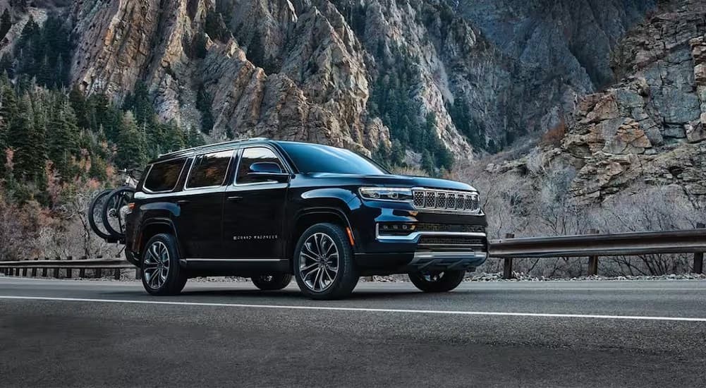 A black 2024 Jeep Grand Wgoneer is shown driving on a highway.