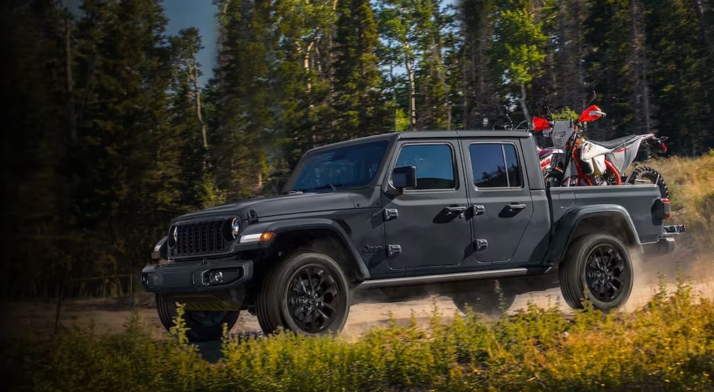 A gray 2024 Jeep Gladiator Nighthawk is shown driving off-road.