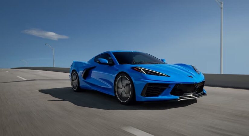 A blue 2025 Chevy Corvette Stingray is shown driving on a highway.