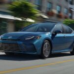 A blue 2025 Toyota Camry for sale is shown from the front at an angle.