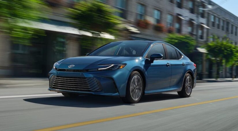 A blue 2025 Toyota Camry for sale is shown from the front at an angle.