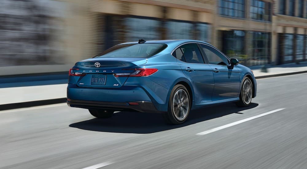 A blue 2025 Toyota Camry XLE is shown from the rear at an angle.