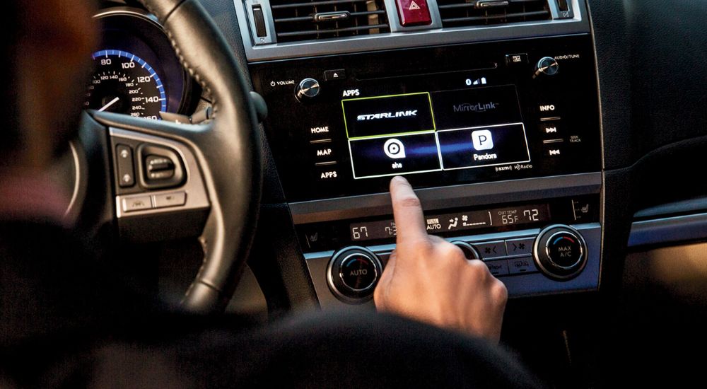 A close up shows a person pressing the STARLINK button in a 2016 Subaru Legacy.