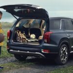 A person loading lumber into the back of a black 2021 Hyundai Palisade.