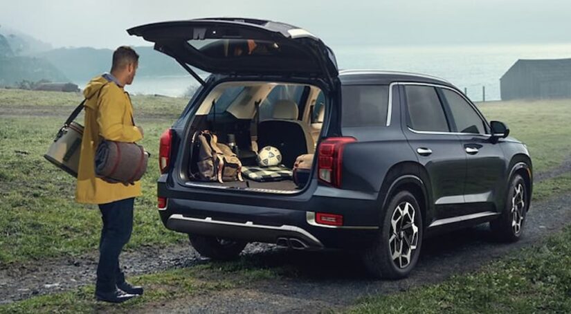 A person loading lumber into the back of a black 2021 Hyundai Palisade.