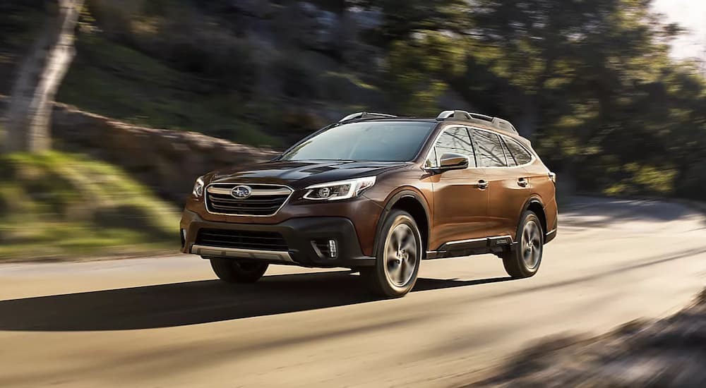 A brown 2022 Subaru Outback Touring is shown driving on a sunny day.