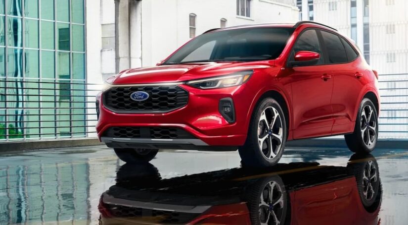 A red 2024 Ford Escape is shown parked on a parking spot near a Ford dealer.