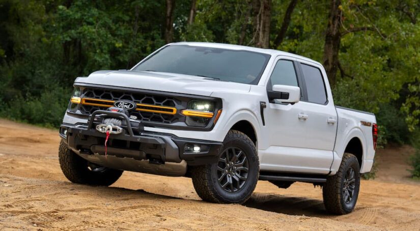 A white 2024 Ford F-150 Tremor is shown from the front at an angle after leaving a dealer that has trucks for sale.