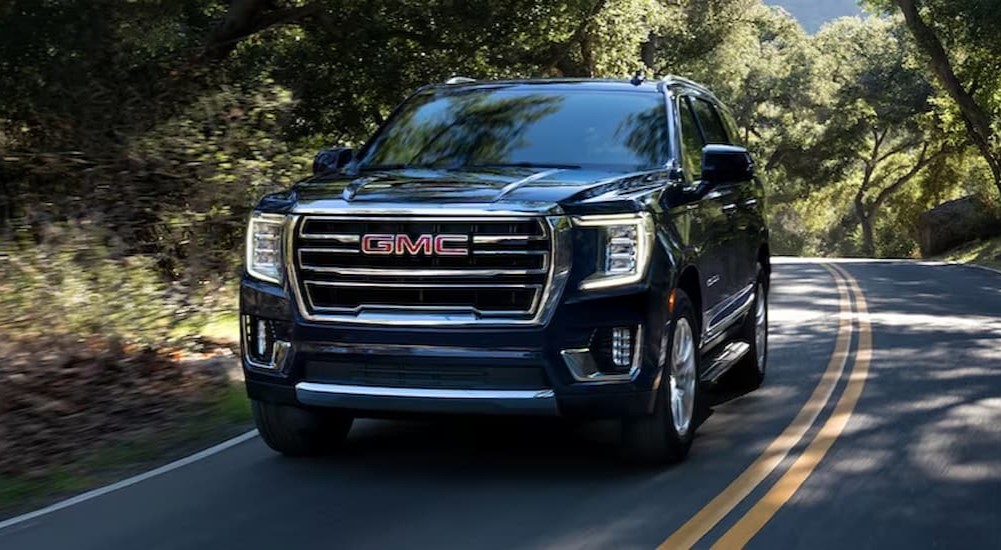 A black 2023 GMC Yukon XL is shown driving on a highway.