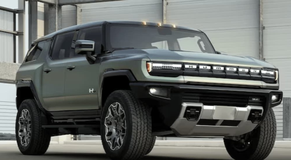 A green 2024 GMC Hummer EV SUV is shown parked in a hangar.