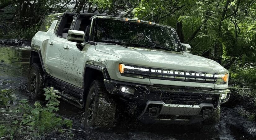 A green 2024 GMC Hummer EV SUV is shown driving off-road.