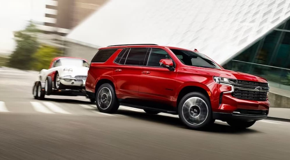 A red 2024 Chevy Tahoe for sale is shown towing a trailer.