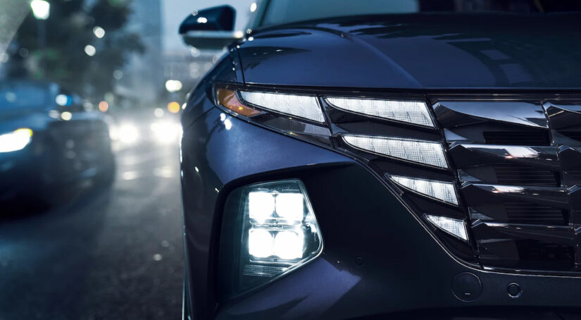 Close-up of the LED headlights on a blue 2024 Hyundai Tucson Hybrid at a Hyundai dealer.