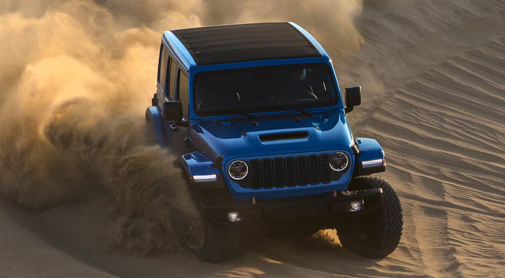 A blue 2024 Jeep Wrangler Rubicon 392 off-roading down a sand dune.