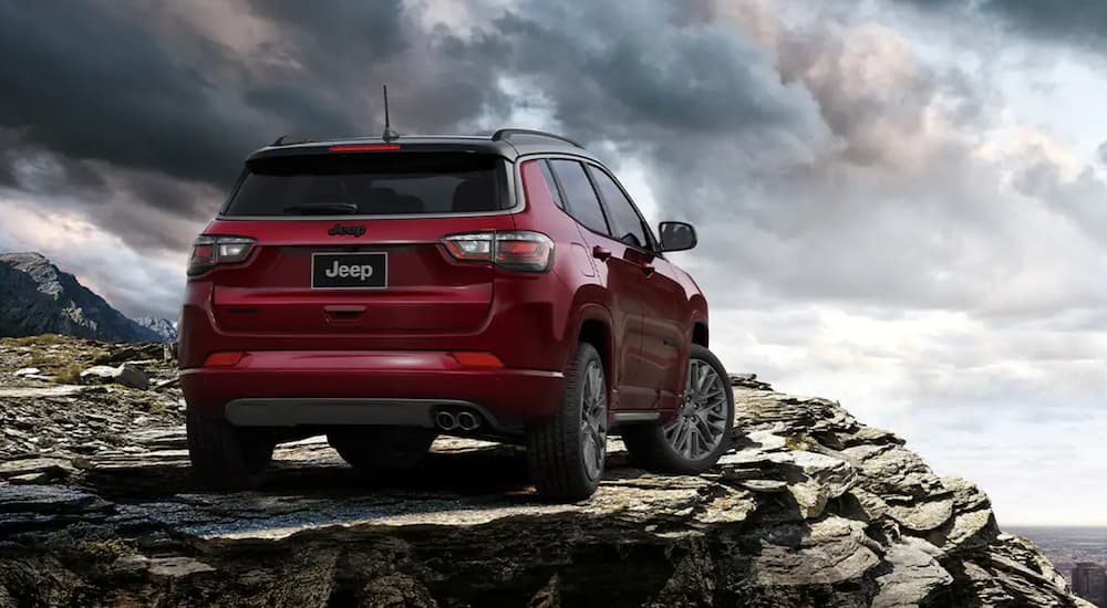 A rear view of a red 2024 Jeep Compass parked at the edge of a cliff.