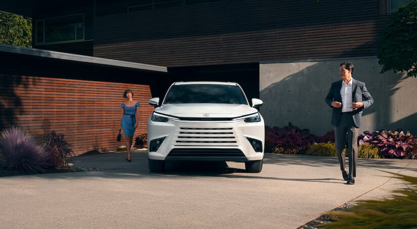 A well-dressed couple walking to the white 2024 Lexus TX parked in their driveway.