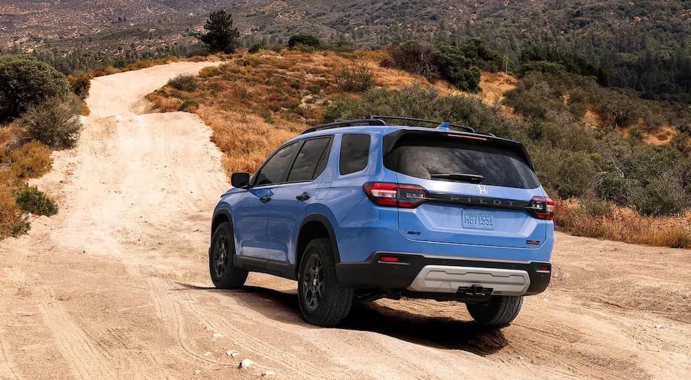 A blue 2024 Honda Pilot Trailsport is shown from the rear at an angle.