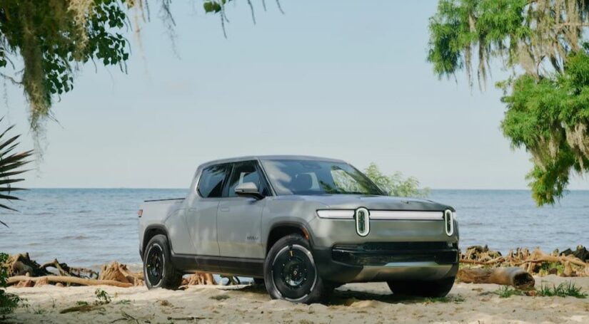 A gray 2024 Rivian R1T is shown parked near an ocean.