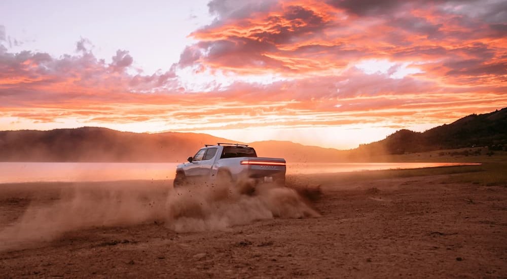 A gray 2024 Rivian R1T is shown driving on sand.