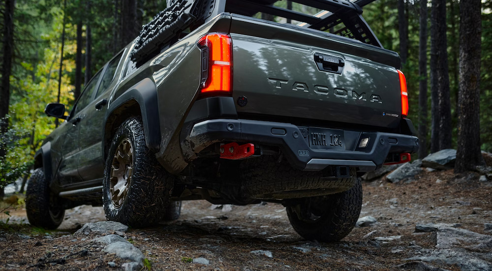 Rear view of a green 2024 Toyota Tacoma iForceMAX Trailhunter in the woods.