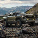 A green 2024 Toyota Tacoma iForceMAX Trailhunter parked on a rocky mountain.