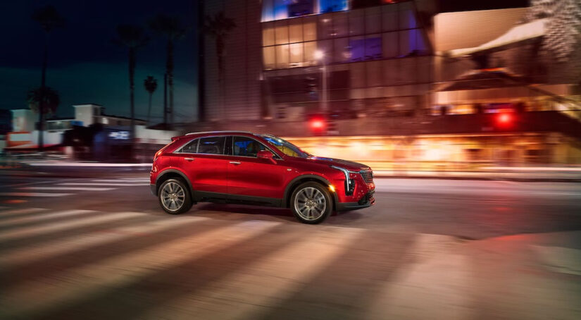 A red 2024 Cadillac XT4 for sale is shown from the side while driving on a city street.