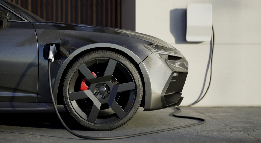 A close-up of a grey car parked in a garage and charging.