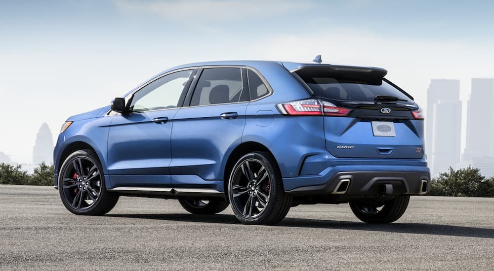 A blue 2020 Ford Edge ST is shown parked near a city.