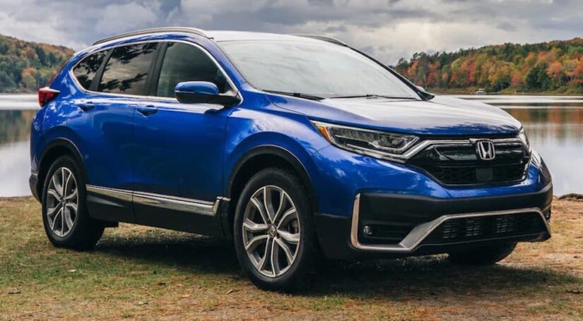 A blue 2022 Honda CR-V Touring parked off-road by a pond.