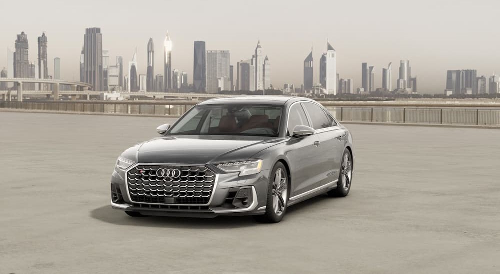 A silver 2024 Audi S8 is shown parked near a city.