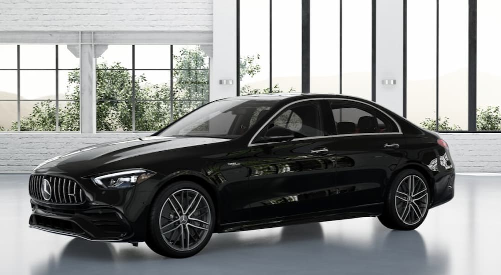 A black 2024 Mercedes-Benz AMG C 43 is shown parked in a room with many windows.