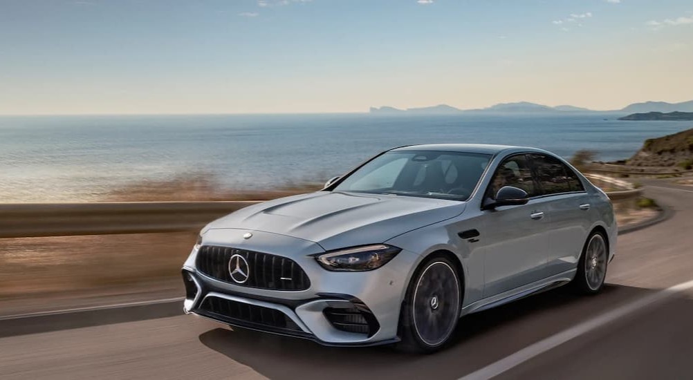 A silver 2024 Mercedes-Benz AMG C 63 S E Performance is shown driving on a highway.