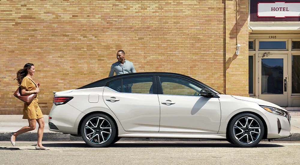 A white 2024 Nissan Sentra is shown parked near two people.