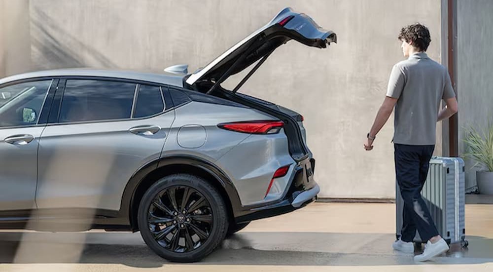 A person is shown opening the hatch on a silver 2025 Buick Envista ST.