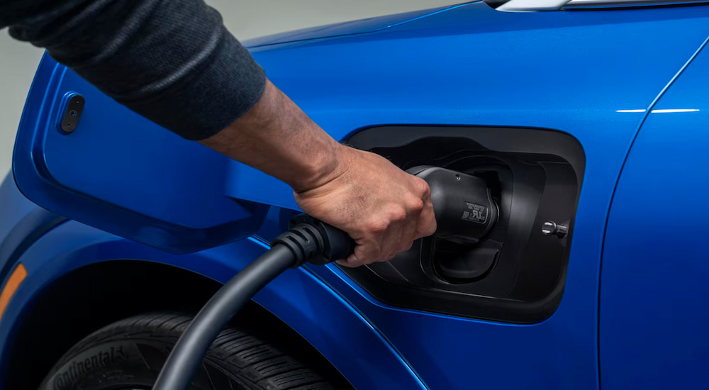 Close-up of the charging port on a blue 2024 Chevy Equinox EV at a Chevy dealer.