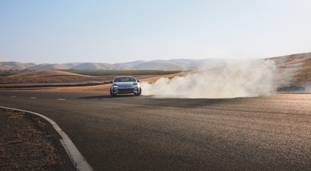 A silver 2022 Subaru BRZ is shown kicking up smoke on a race track.