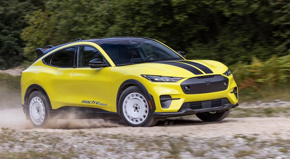 A yellow 2024 Ford Mustang Mach-E GT Rally Edition driving on a dirt path.