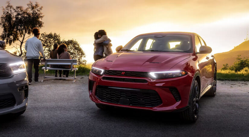 A red 2024 Dodge Hornet parked on a mountaintop overlook at sunset.