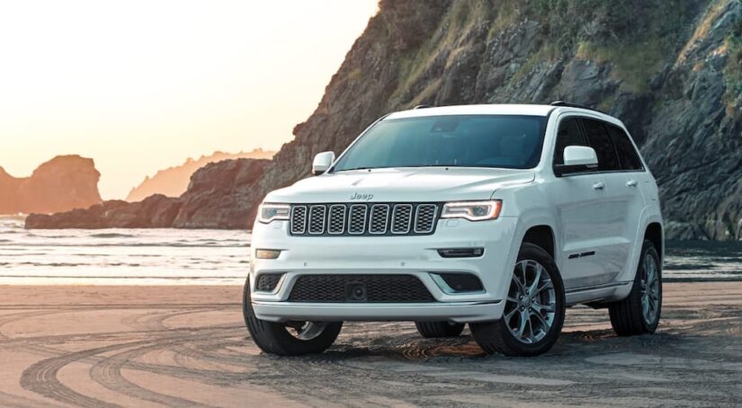 A white 2020 Jeep Grand Cherokee Summit parked on a lake shore.