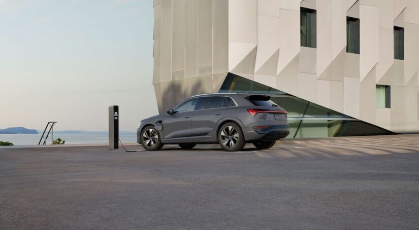 A gray 2024 Audi Q8 e-tron is shown charging near an ocean.