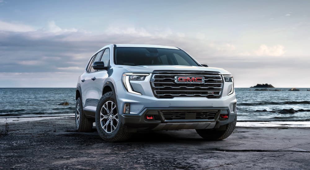 A white 2025 GMC Acadia AT4 is shown from the front at an angle.