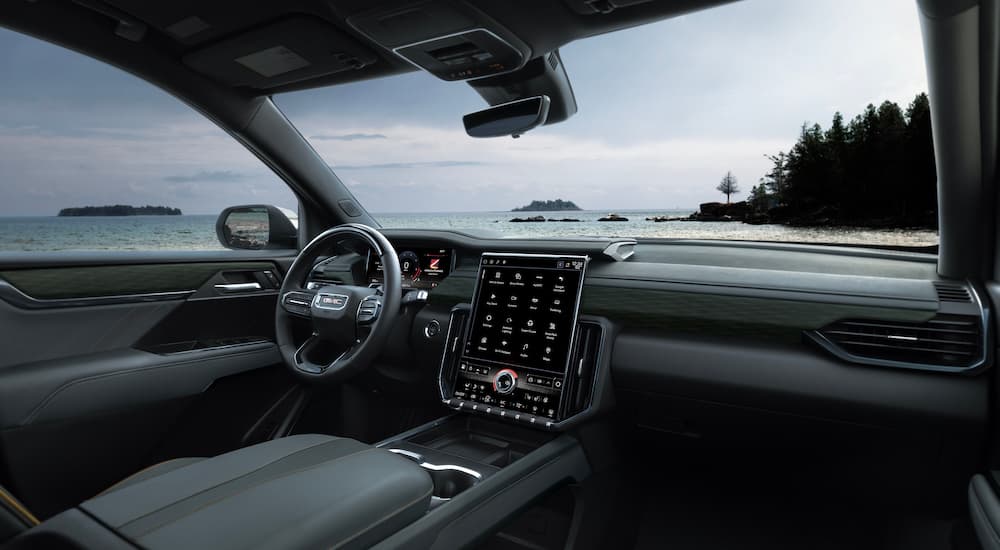 The grey interior of a 2025 GMC Acadia AT4 is shown from the passenger seat.