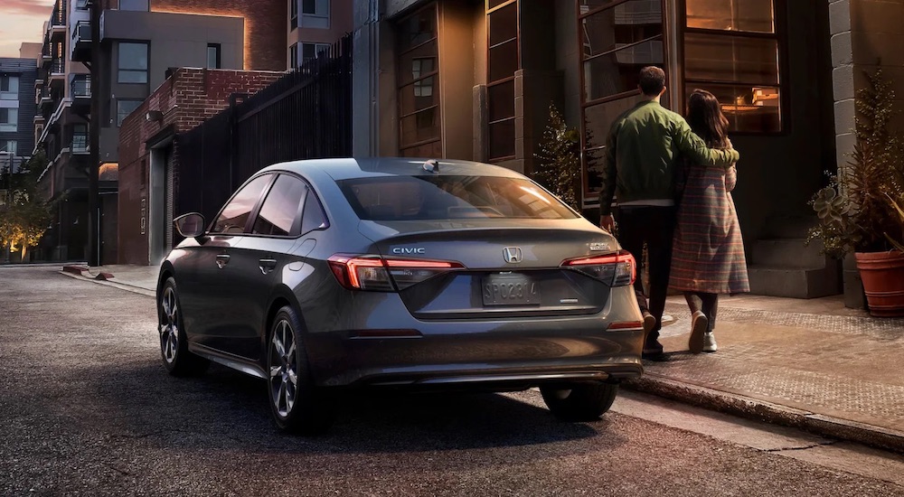 A grey 2025 Honda Civic Sport Touring Hybrid is shown from the rear at an angle after leaving a Honda dealer.