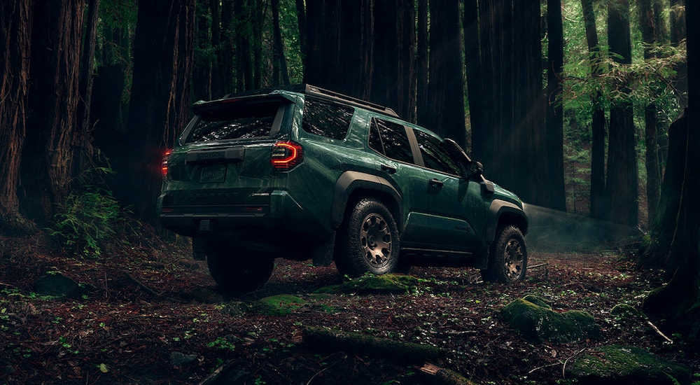 Rear angle view of a green 2025 Toyota 4Runner Trailhunter parked in a forest.