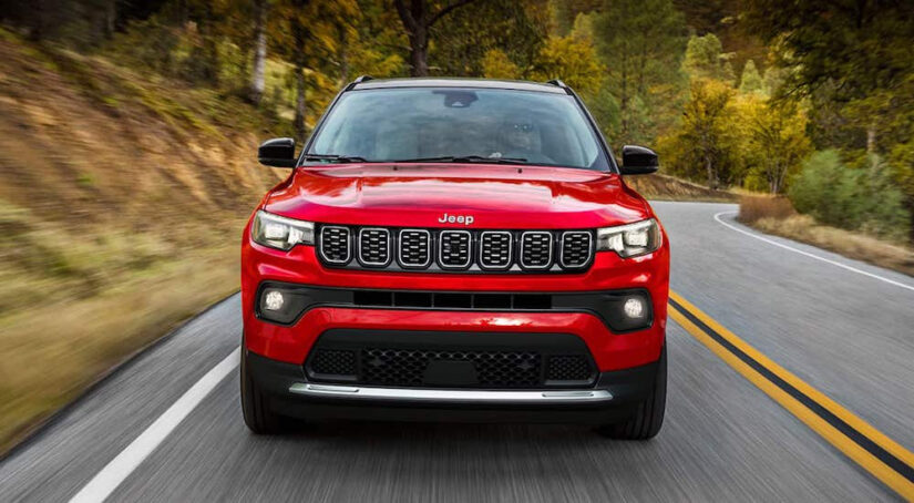 A red 2024 Jeep Compass is shown from the front after leaving a Jeep dealer.