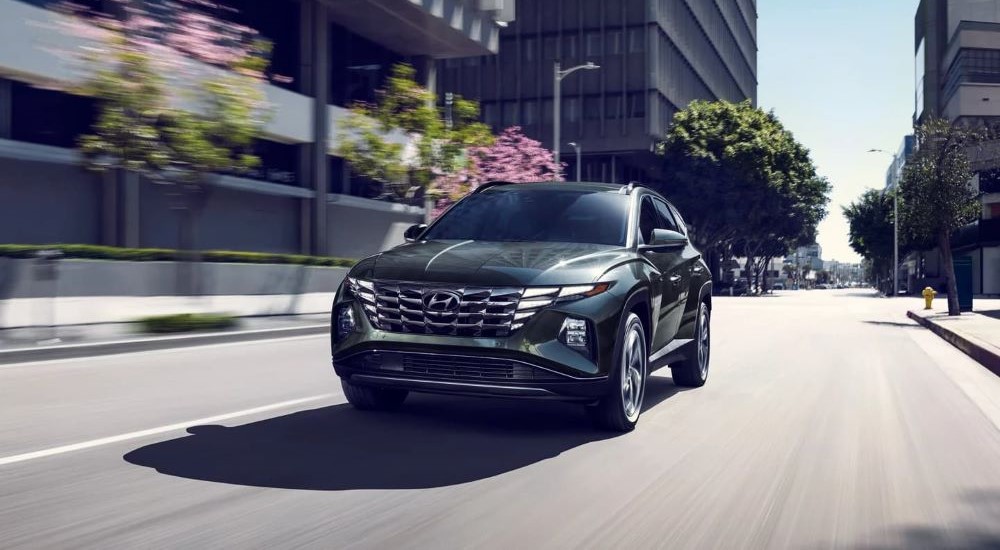 A green 2022 Hyundai Tucson Hybrid Limited is shown driving to view used SUVs for sale.