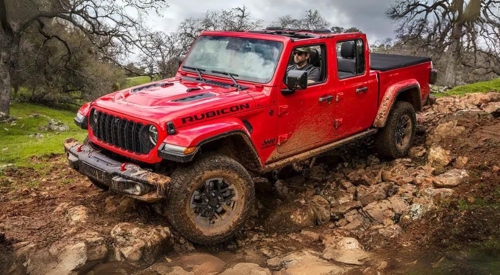 A red 2024 Jeep Gladiator Rubicon is shown off-roading.