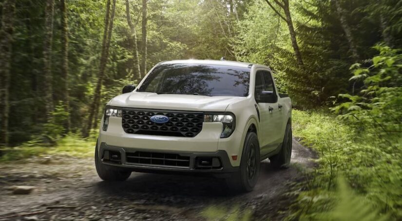 A white 2025 Ford Maverick XLT is shown driving on a dirt path.