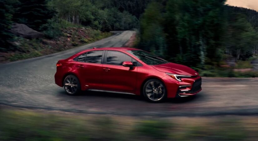 A red 2025 Toyota Corolla Hybrid is shown driving on a backroad.